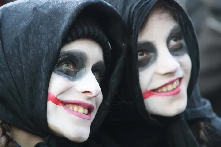 Due maschere del Carnevale di Satriano con il volto dipinto di bianco e nero e il capo coperto da un cappuccio scuro