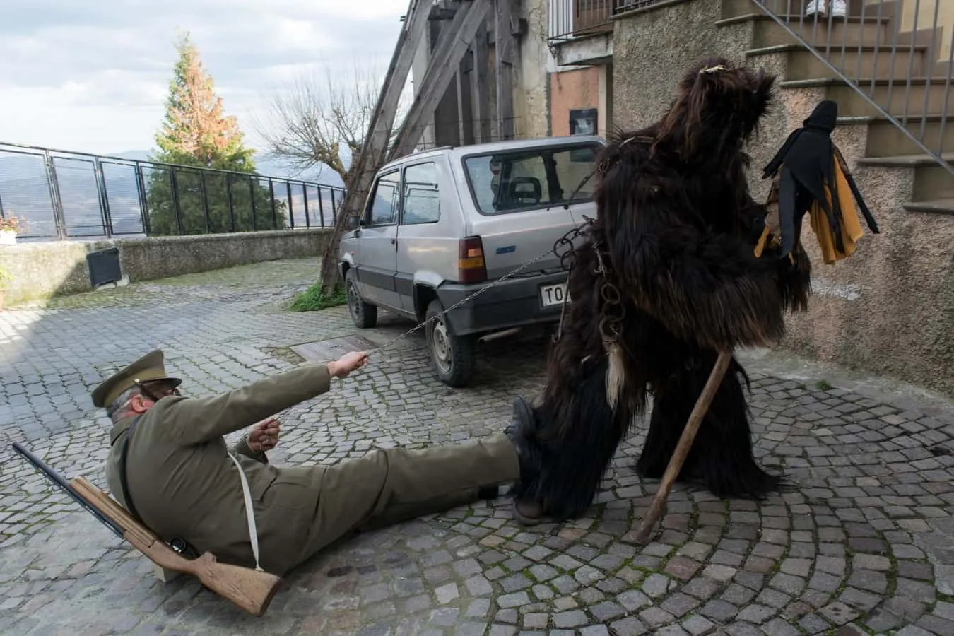 L’Urs, l’orso dal folto manto scuro, sovrasta un figurante disteso a terra in una via di Teana